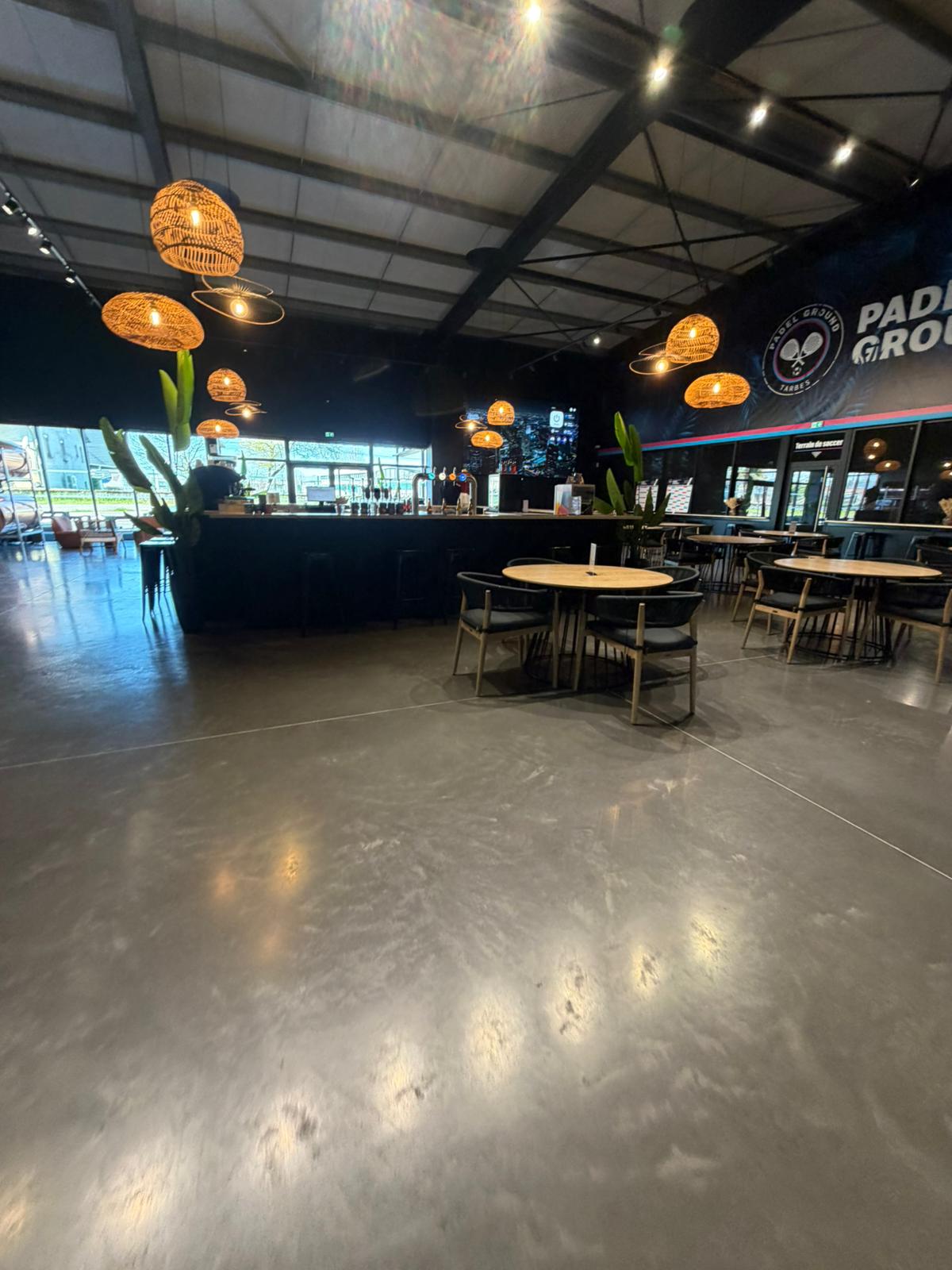 Padel Ground Tarbes — seating area with branded wall